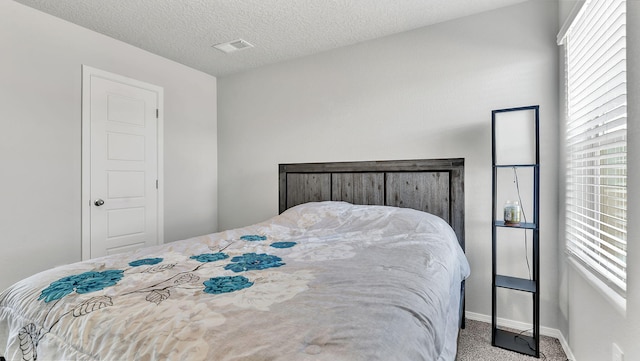 bedroom with visible vents, multiple windows, a textured ceiling, and carpet floors