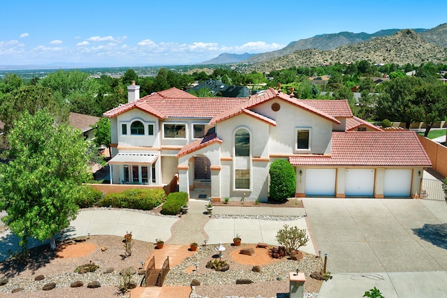 mediterranean / spanish-style home featuring a garage, driveway, a chimney, and a tiled roof