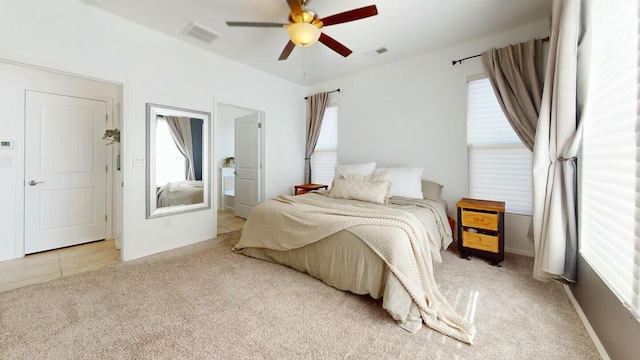 carpeted bedroom featuring ensuite bath, visible vents, and a ceiling fan