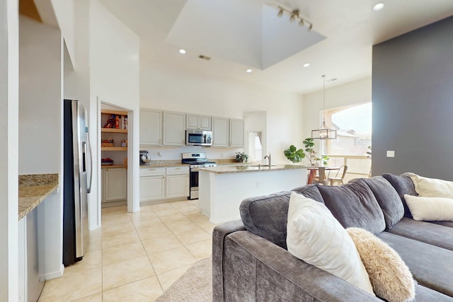 living area with recessed lighting, light tile patterned flooring, visible vents, and a high ceiling