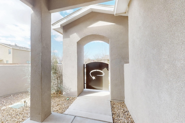 doorway to property featuring fence and stucco siding