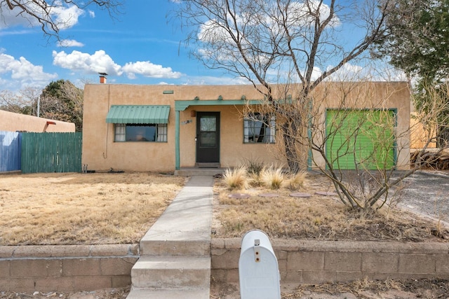 pueblo-style home with fence and stucco siding