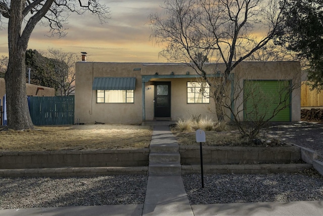 pueblo-style house with fence and stucco siding