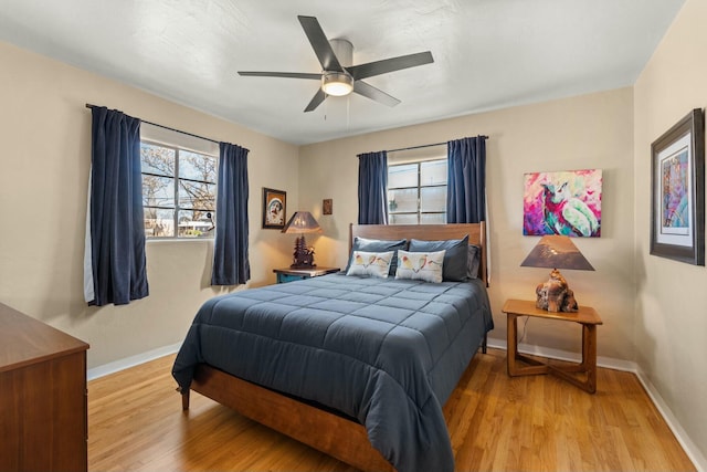 bedroom with a ceiling fan, baseboards, and wood finished floors