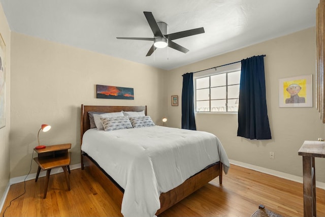 bedroom featuring a ceiling fan, baseboards, and wood finished floors