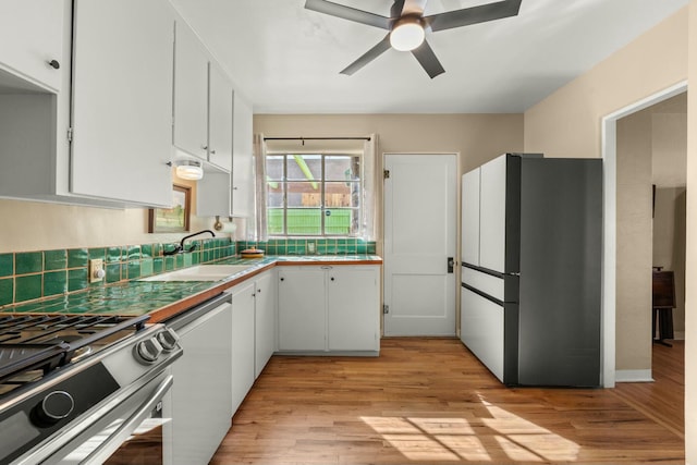 kitchen featuring freestanding refrigerator, white cabinets, a sink, light wood-type flooring, and dishwasher