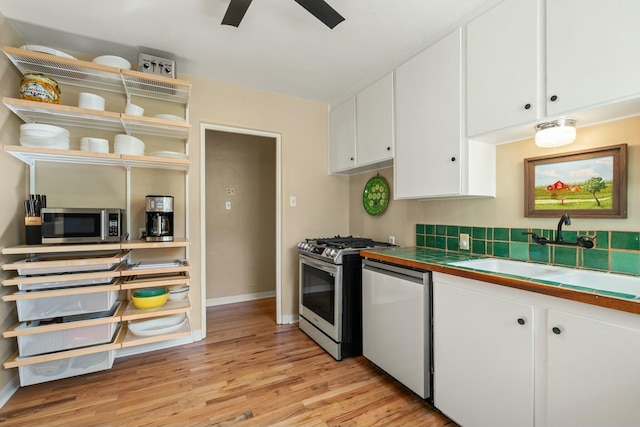 kitchen featuring a sink, white cabinetry, appliances with stainless steel finishes, tile counters, and light wood finished floors