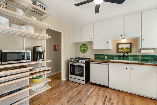 kitchen featuring a sink, white cabinets, appliances with stainless steel finishes, tile counters, and open shelves