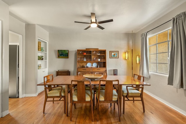 dining area with built in features, baseboards, ceiling fan, and light wood finished floors