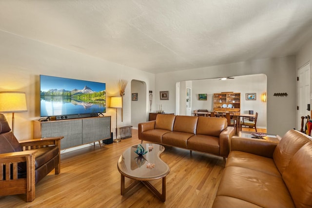 living area with light wood-style floors, arched walkways, and a textured ceiling