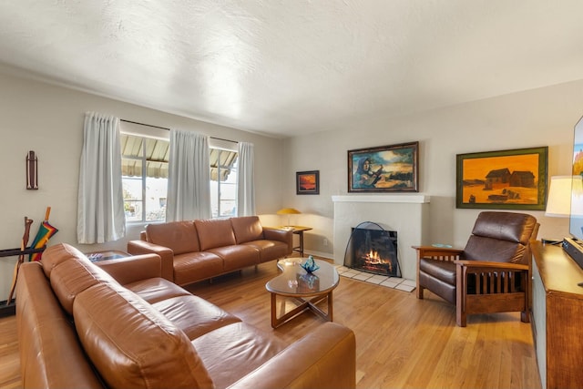 living room featuring light wood finished floors, a fireplace with flush hearth, and a textured ceiling