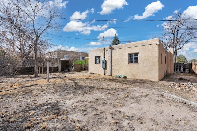 rear view of house with fence and stucco siding