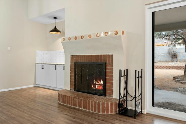 living area featuring a fireplace, baseboards, and wood finished floors