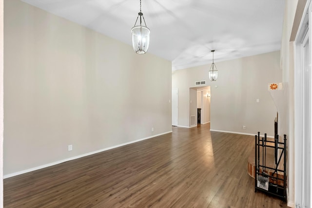 unfurnished room featuring a chandelier, dark wood finished floors, visible vents, and baseboards