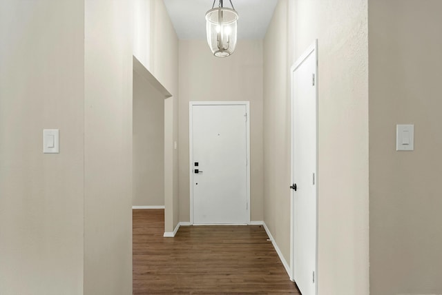 doorway to outside with baseboards, an inviting chandelier, and wood finished floors