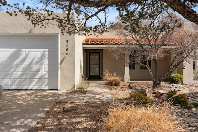 view of front of home featuring an attached garage, a tile roof, and stucco siding