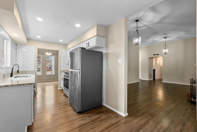 kitchen with appliances with stainless steel finishes, decorative backsplash, a sink, and wood finished floors