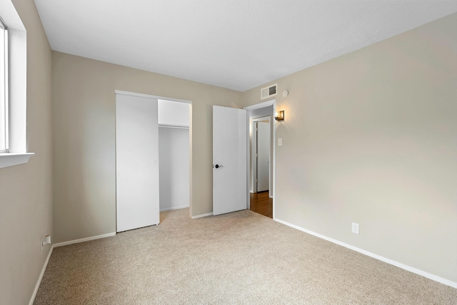 unfurnished bedroom featuring carpet floors, a closet, visible vents, and baseboards