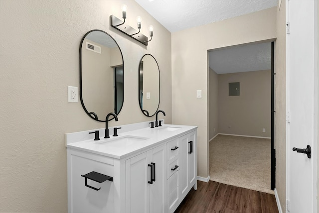 bathroom featuring double vanity, visible vents, a sink, and wood finished floors