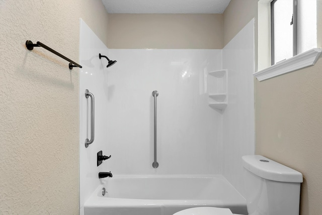 bathroom featuring a textured wall, toilet, and shower / bathtub combination