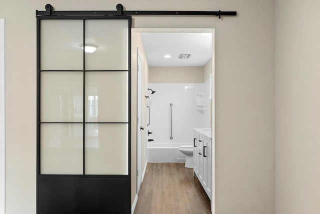 bathroom featuring toilet, shower / bath combination, wood finished floors, and vanity