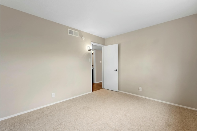 carpeted spare room featuring visible vents and baseboards