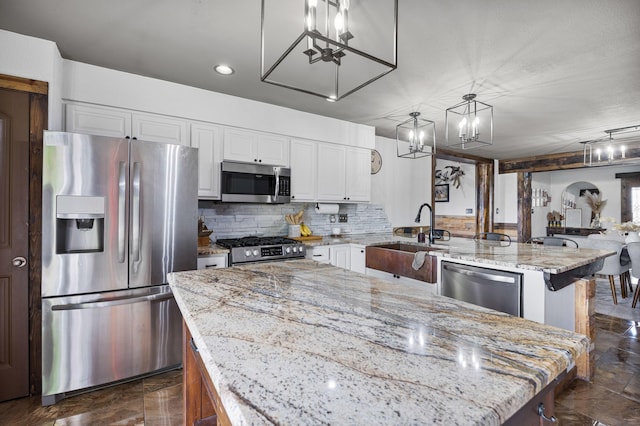 kitchen with a sink, a kitchen island, backsplash, appliances with stainless steel finishes, and white cabinets