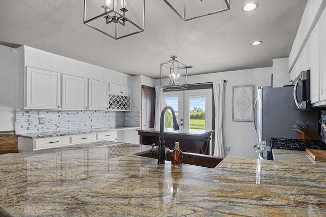 kitchen with white cabinets, light stone counters, backsplash, and stainless steel appliances