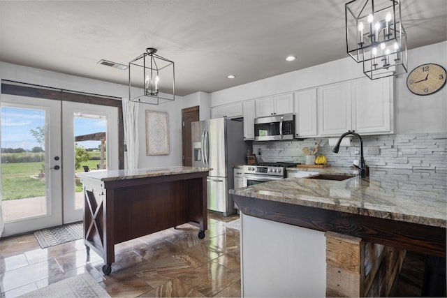 kitchen with visible vents, decorative backsplash, a notable chandelier, stainless steel appliances, and a sink