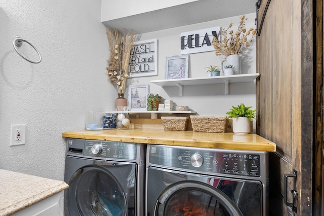 clothes washing area with washer and dryer, laundry area, and a textured wall