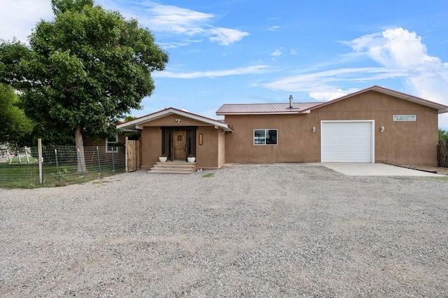 single story home with fence, stucco siding, metal roof, a garage, and driveway