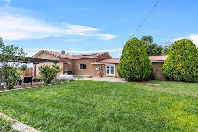 back of property featuring a patio, a yard, stucco siding, french doors, and roof mounted solar panels