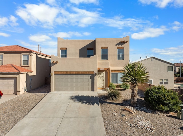 pueblo-style home featuring a garage, driveway, and stucco siding