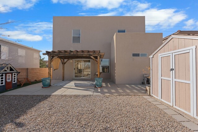 rear view of house with an outbuilding, fence, a shed, a pergola, and a patio area