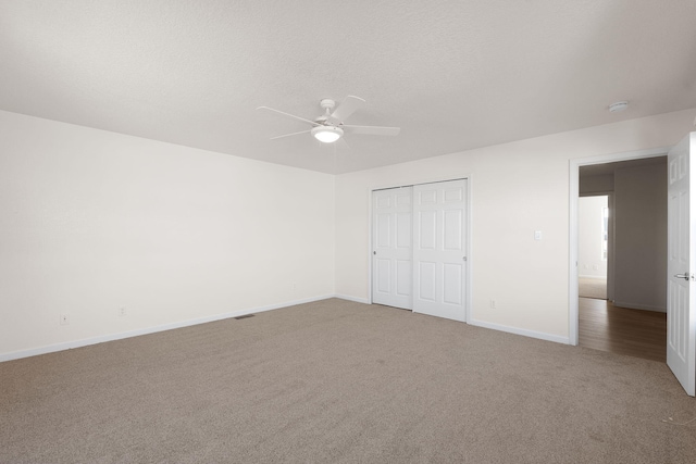 unfurnished bedroom with a ceiling fan, a textured ceiling, a closet, carpet floors, and baseboards