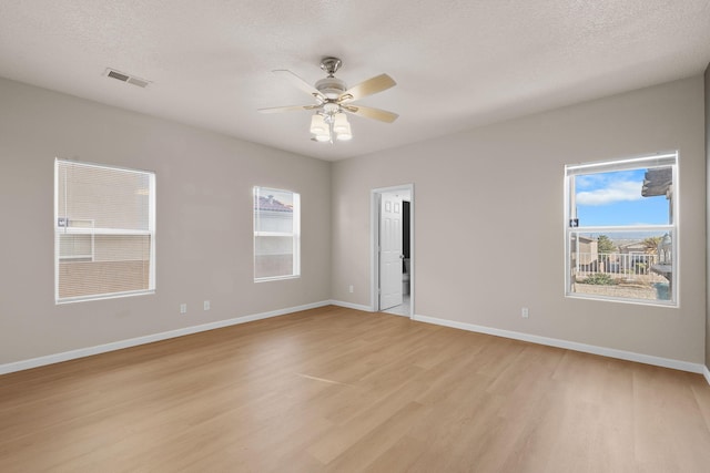 spare room with visible vents, a ceiling fan, a textured ceiling, light wood finished floors, and baseboards