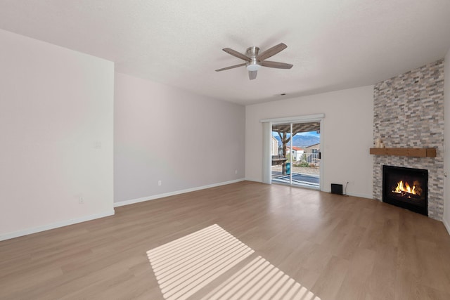 unfurnished living room featuring light wood finished floors, a fireplace, baseboards, and ceiling fan