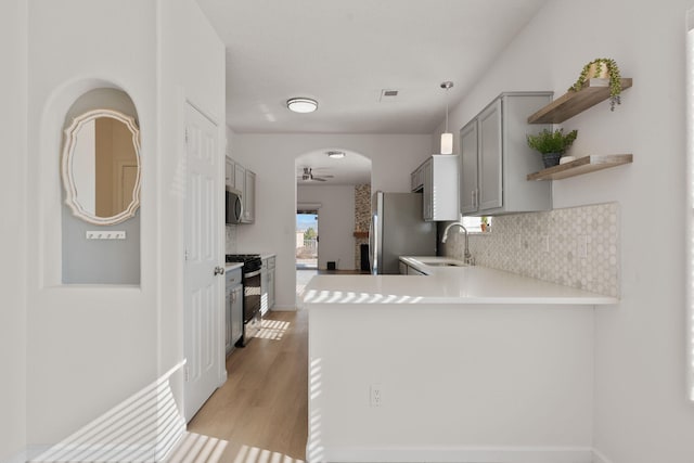 8104 Sleeping Bear Dr NW, Albuquerque, NM 87120 - kitchen featuring stainless steel appliances, open shelves, tasteful backsplash, gray cabinetry, and a peninsula