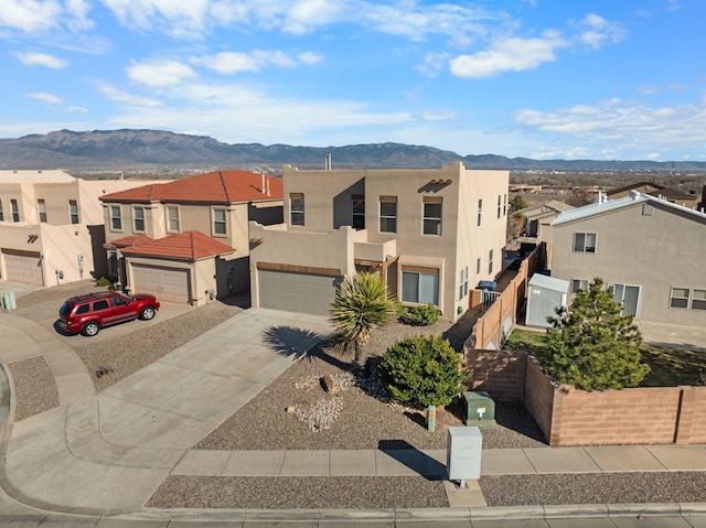 southwest-style home featuring stucco siding, driveway, a mountain view, a residential view, and a garage