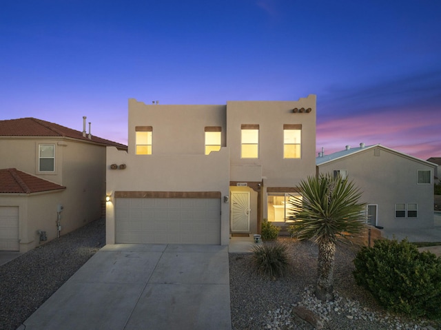 pueblo-style house with stucco siding, concrete driveway, and an attached garage