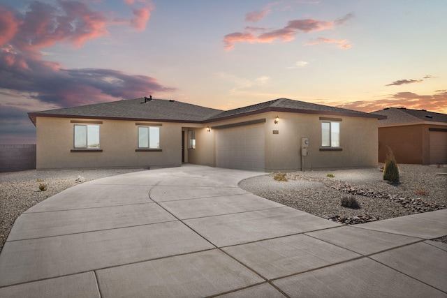 view of front facade with stucco siding, concrete driveway, an attached garage, and a shingled roof