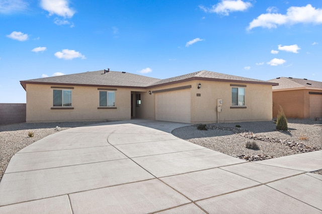 view of front facade featuring stucco siding, fence, concrete driveway, an attached garage, and a shingled roof