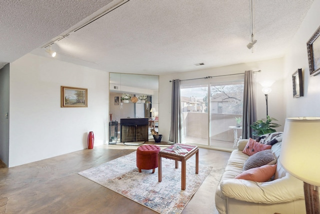 living room featuring rail lighting, finished concrete floors, visible vents, and a textured ceiling