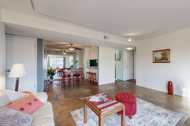 living area featuring finished concrete floors, visible vents, and a textured ceiling