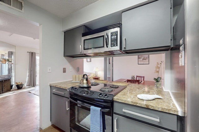 kitchen featuring visible vents, light stone counters, gray cabinets, stainless steel appliances, and a textured ceiling