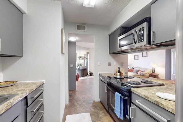 kitchen with visible vents, stainless steel microwave, black / electric stove, a textured ceiling, and concrete floors