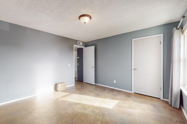 unfurnished room featuring baseboards, a textured ceiling, visible vents, and concrete flooring