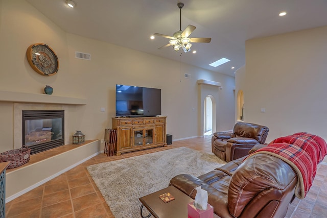 living room featuring arched walkways, a fireplace, visible vents, a ceiling fan, and tile patterned floors