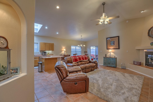 living room with light tile patterned floors, lofted ceiling, a glass covered fireplace, baseboards, and ceiling fan with notable chandelier