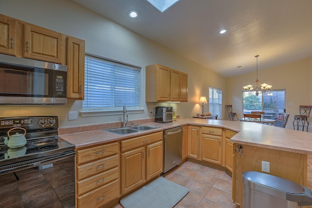 kitchen with lofted ceiling, appliances with stainless steel finishes, a peninsula, a chandelier, and a sink